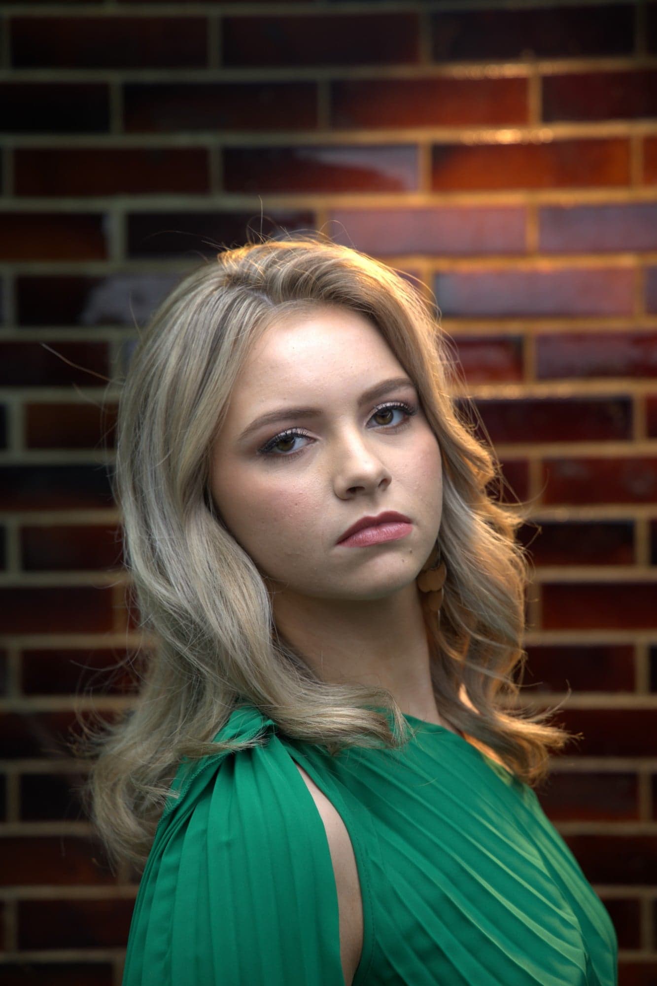 Portrait in a green pleated top against a glazed brick wall